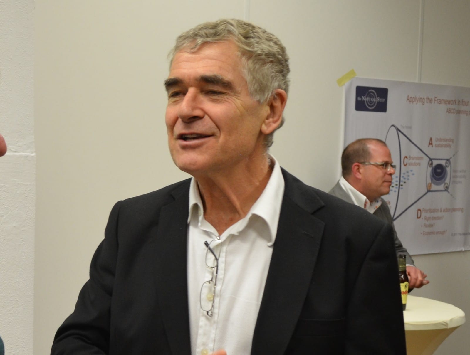 Karl-Henrik Robert in gesprek tijdens de College Tour in Nederland in 2013, met achter hem een poster van de ABCD-planningsmethode